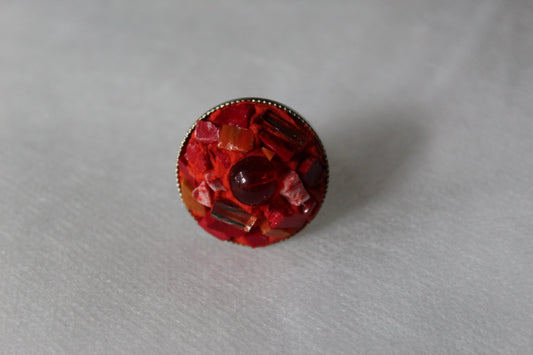 Bague en micromosaïque rouge avec émaux vénitiens, miroirs, émaux céramiques et une perle centrale en verre rouge sur une base réglable en acier inoxydable hypoallergénique.