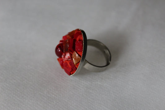 Bague en micromosaïque rouge avec émaux vénitiens, miroirs, émaux céramiques et une perle centrale en verre rouge sur une base réglable en acier inoxydable hypoallergénique.