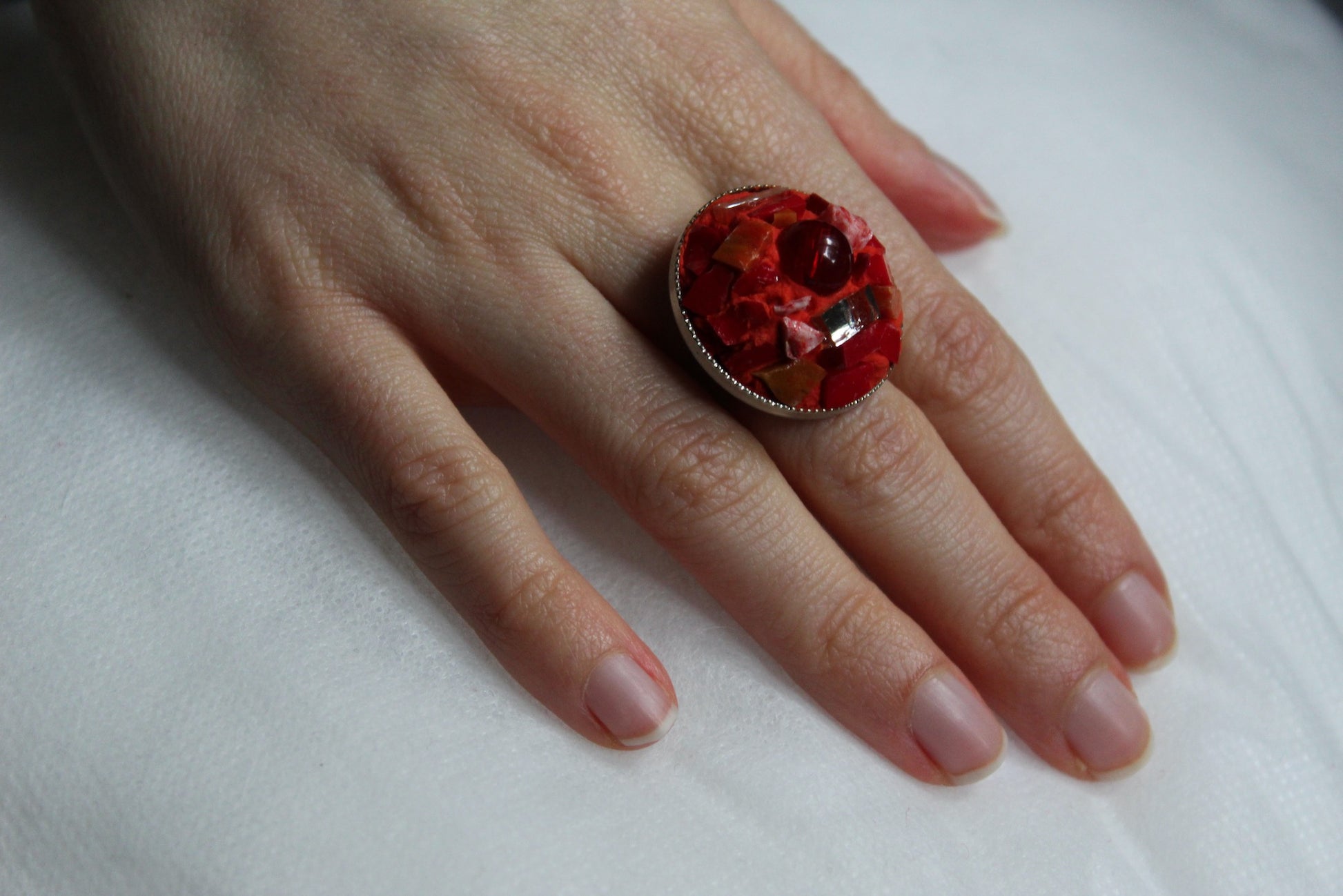 Anello in micromosaico rosso con specchietti indossato su mano