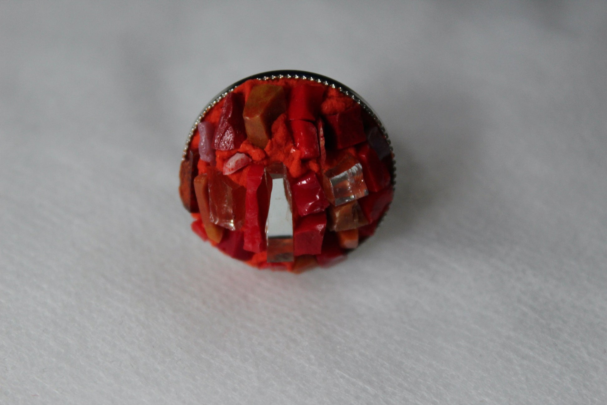 Anello in micromosaico rosso con specchietti su sfondo bianco vista frontale