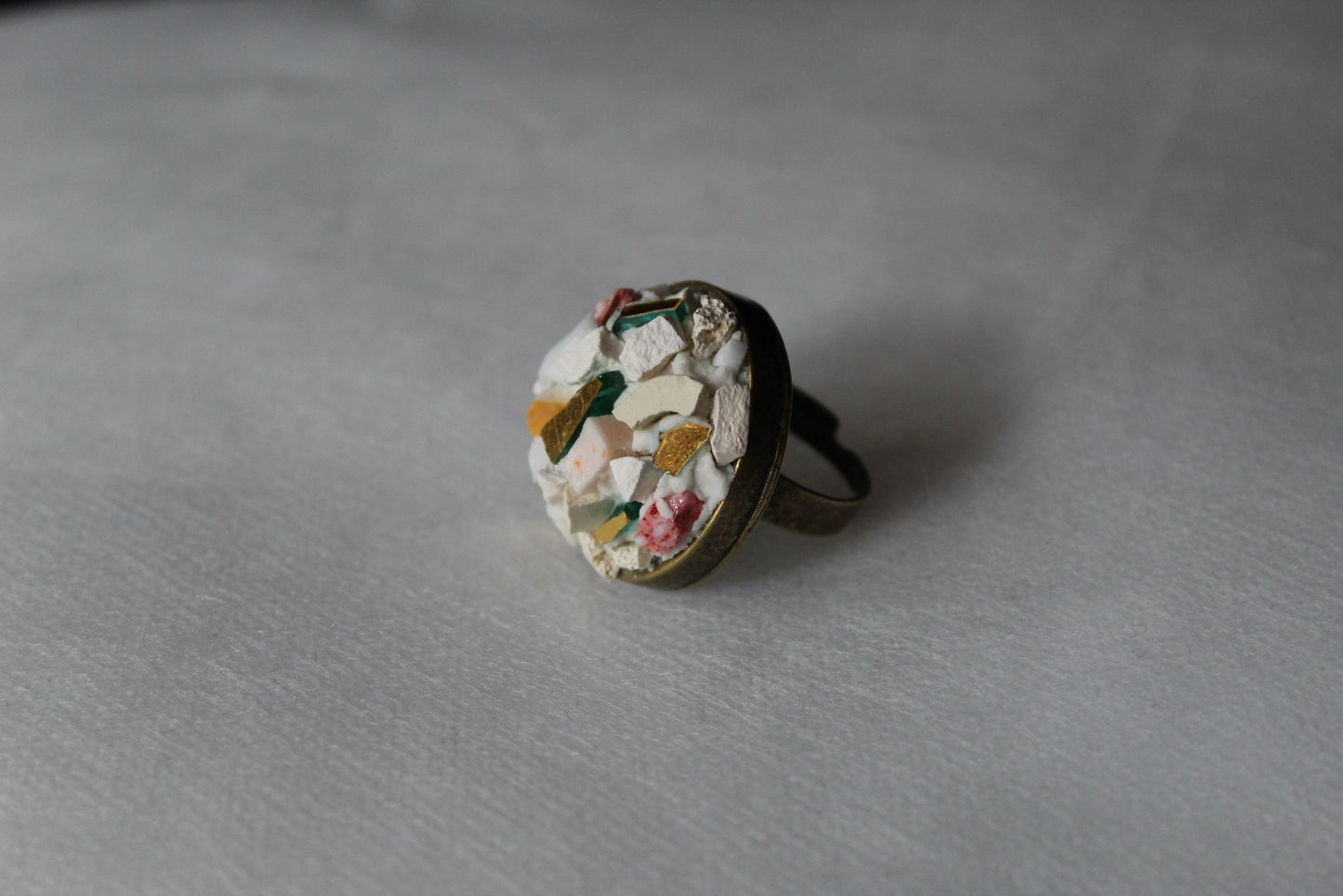 Anello in micromosaico bianco base ottone su sfondo bianco vista laterale sinistra