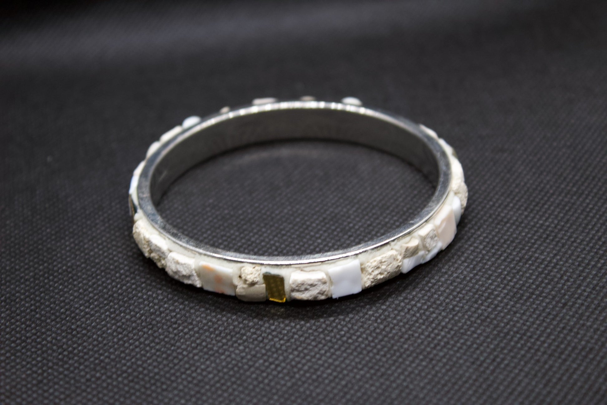 Bracciale bianco in micromosaico con oro puro su sfondo nero vista frontale