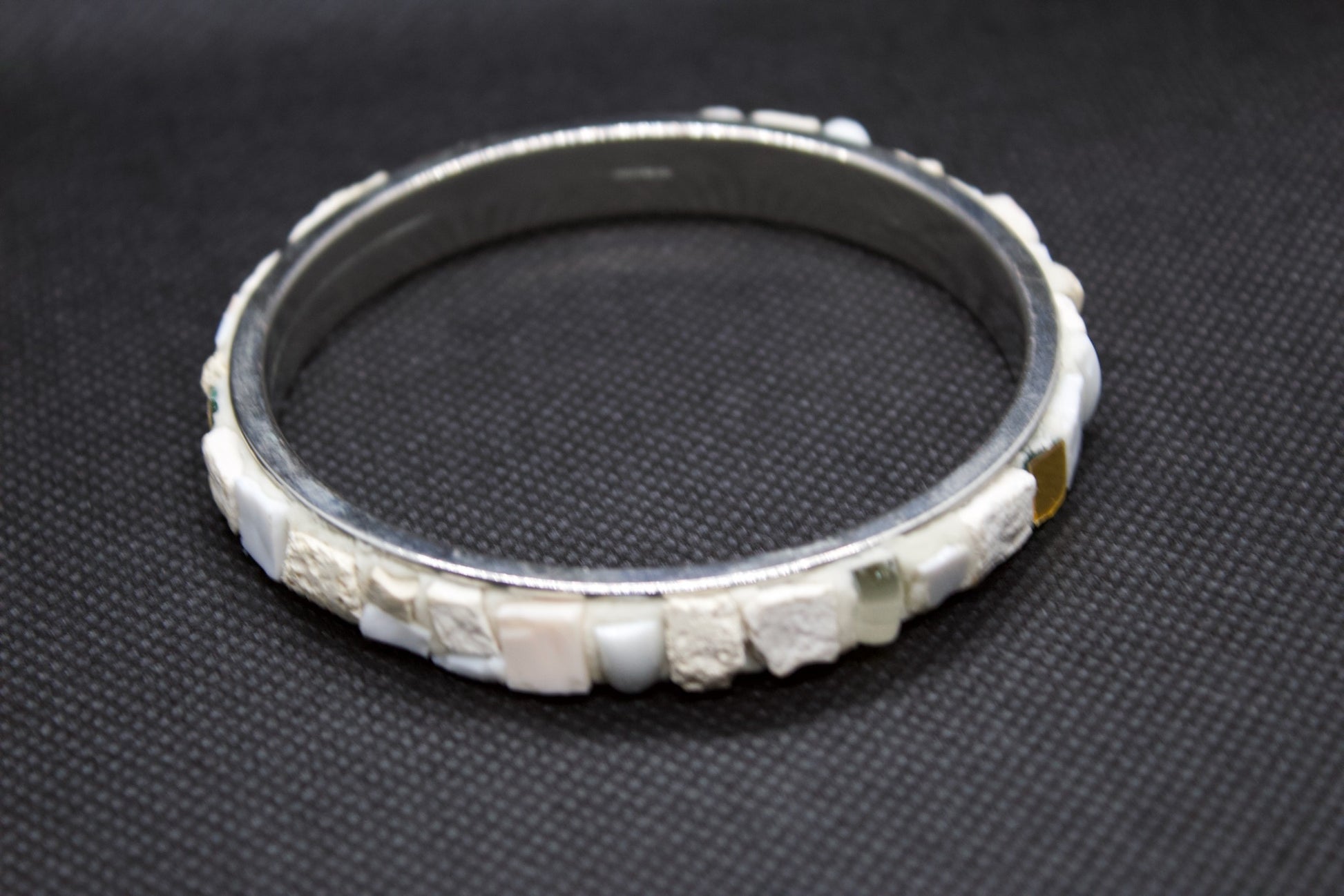 Bracciale bianco in micromosaico con oro puro su sfondo nero vista frontale