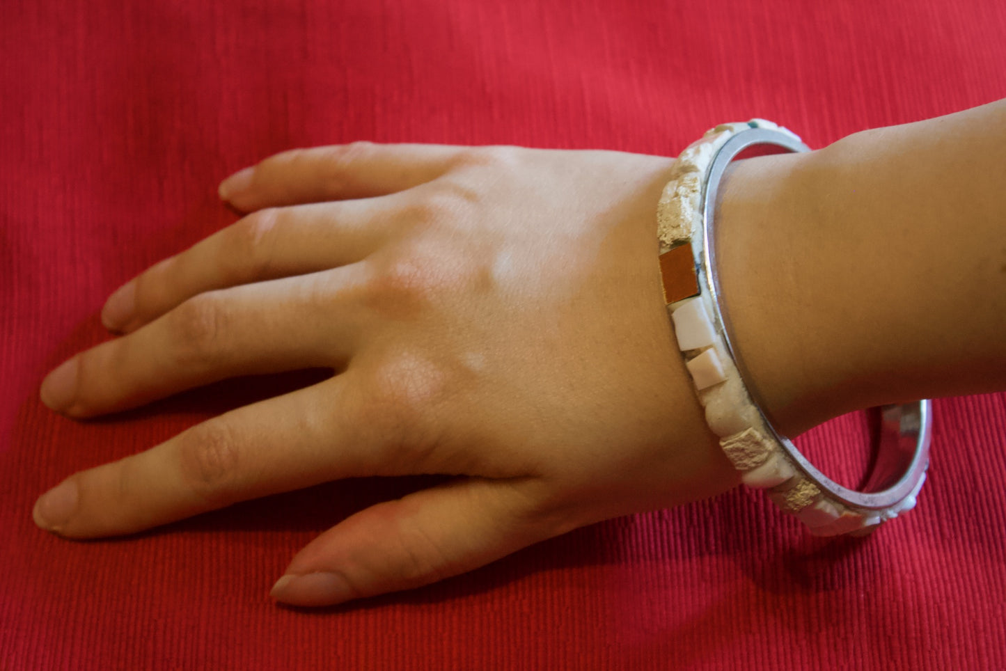 Bracciale bianco in micromosaico con oro puro indossato sul polso