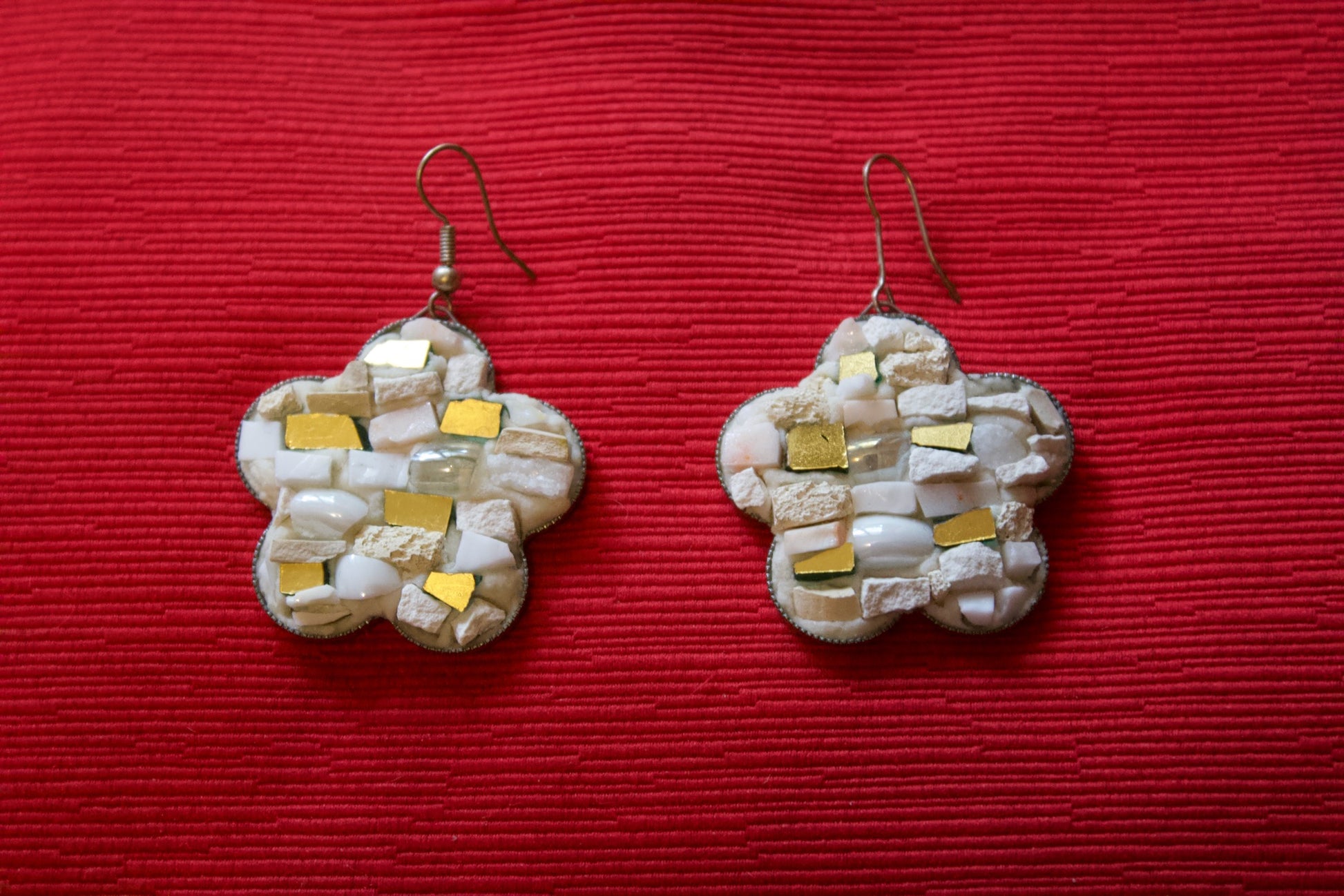 Orecchini a fiore bianchi in micromosaico su sfondo rosso vista frontale