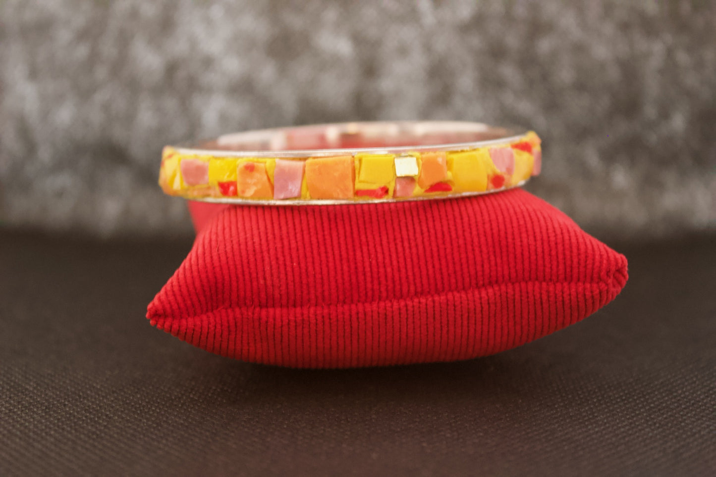 Bracciale giallo arancio in micromosaico su sfondo nero vista frontale